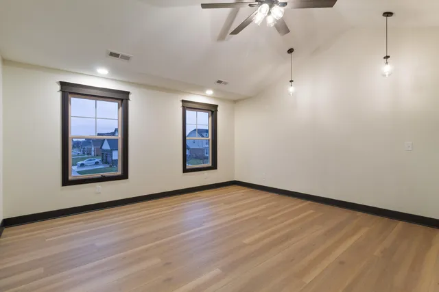 a view of an empty room with a window and wooden floor