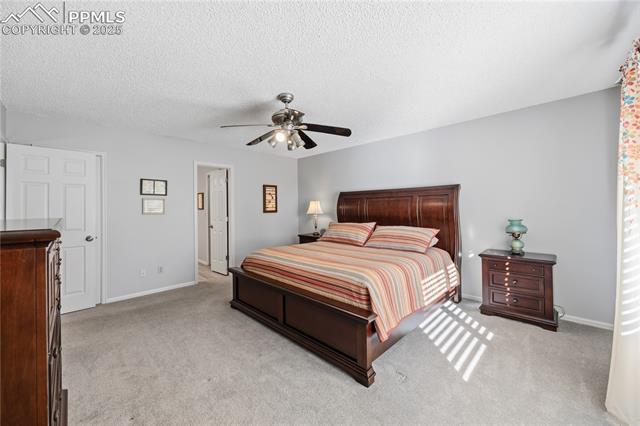 2135 Glenhill Road Colorado Springs, CO 80906 - Photo 21 of 50 Bedroom featuring light colored carpet, a textured ceiling, and a ceiling fan