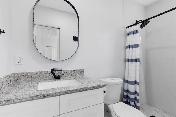 a bathroom with a granite countertop sink mirror vanity and toilet