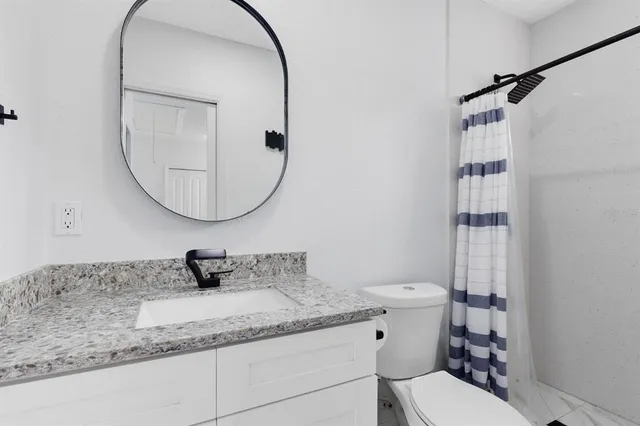 a bathroom with a granite countertop sink mirror vanity and toilet