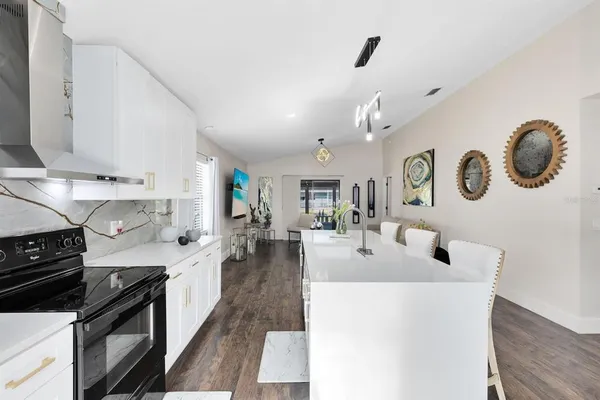 a large white kitchen with a large oven a stove a sink a dining table and chairs