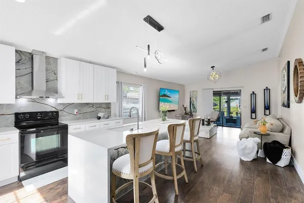 a kitchen with stainless steel appliances a stove a sink dishwasher a dining table and chairs with wooden floor