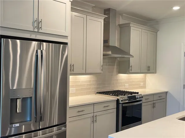 a kitchen with a sink a refrigerator and white cabinets