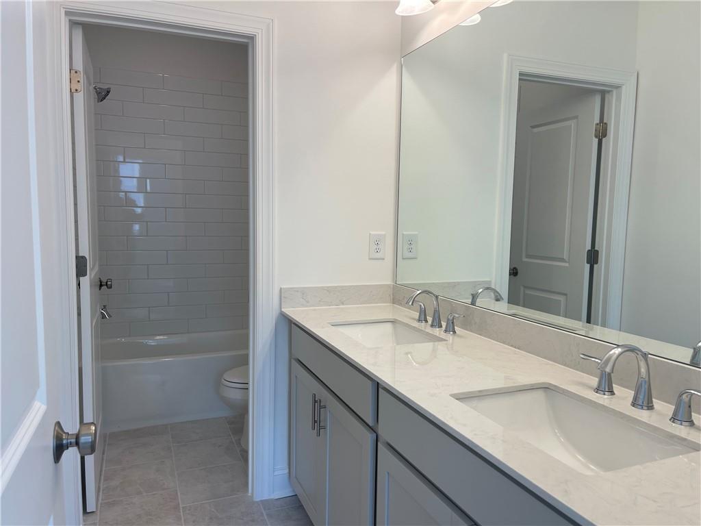 4807 Larkin Pass Buford, GA 30518 - Photo 51 of 58 a bathroom with a granite countertop sink a toilet and shower