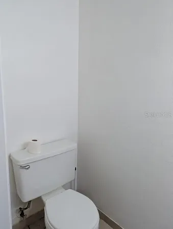 a white toilet sitting next to a white wall