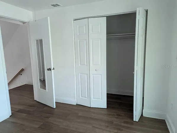 a view of an empty room with wooden floor and a hallway