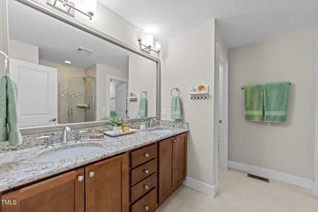 a bathroom with a granite countertop double vanity sink and a mirror