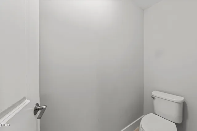 a white toilet sitting next to a white wall