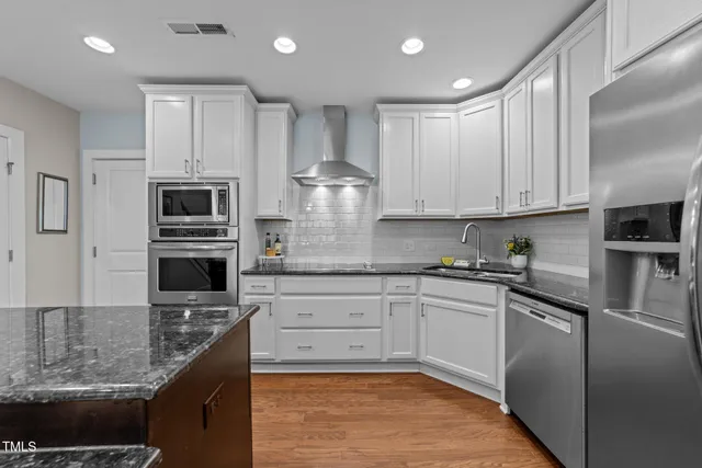 a kitchen with stainless steel appliances granite countertop a stove sink and cabinets