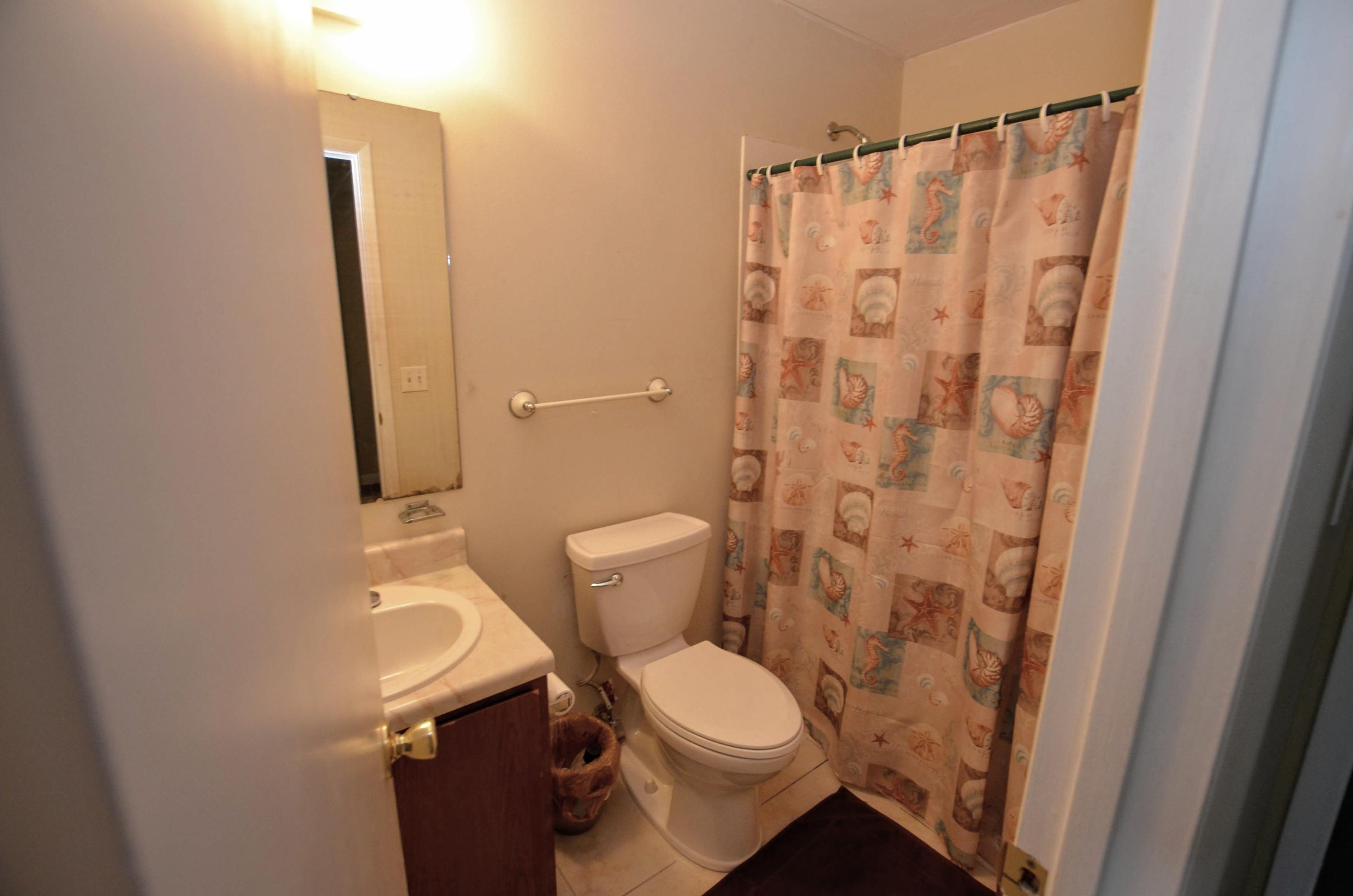 81 Cross Creek Road, Unit 22 Miramar Beach, FL 32550 - Photo 11 of 13 a white toilet sitting next to a shower curtain