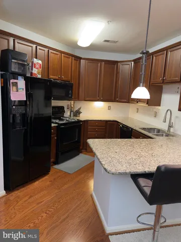 a kitchen with stainless steel appliances granite countertop a sink dishwasher stove and refrigerator with wooden floor