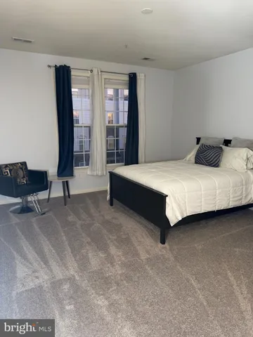 a spacious bedroom with a bed and a dresser in it