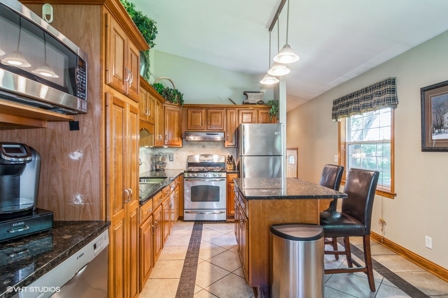 28 Jack Street Plano, IL 60545 - Photo 5 of 21 a kitchen with stainless steel appliances granite countertop a refrigerator a stove a sink dishwasher and wooden cabinets with wooden floor