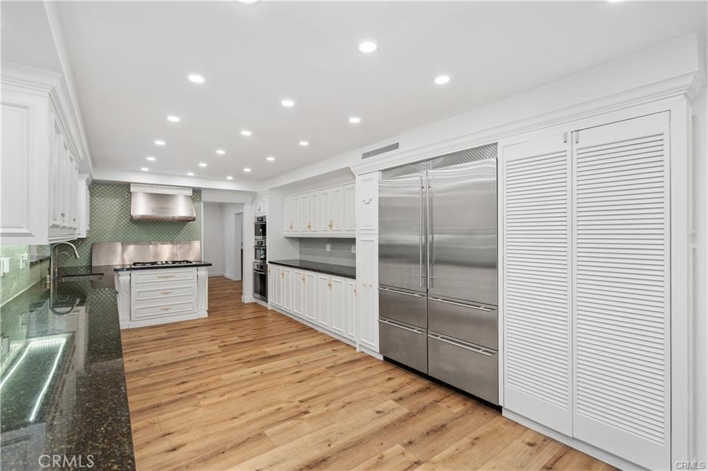 119 Bell Cyn Road Bell Canyon, CA 91307 - Photo 22 of 39 a large kitchen with kitchen island a stove a sink a refrigerator and white cabinets with wooden floor