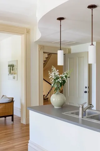 a kitchen with a sink a stove a refrigerator and white cabinets with wooden floor