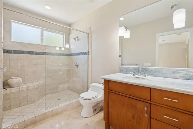 a bathroom with a granite countertop sink a toilet and shower