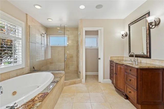 a bathroom with a granite countertop tub sink shower and mirror