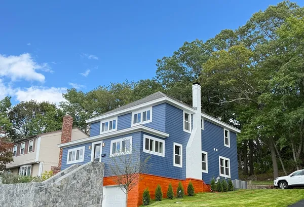 a front view of a house with garden and trees