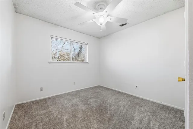 an empty room with a fan & a window