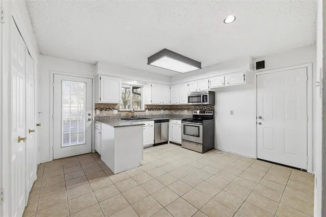 a kitchen with granite countertop white cabinets white appliances with a sink and dishwasher