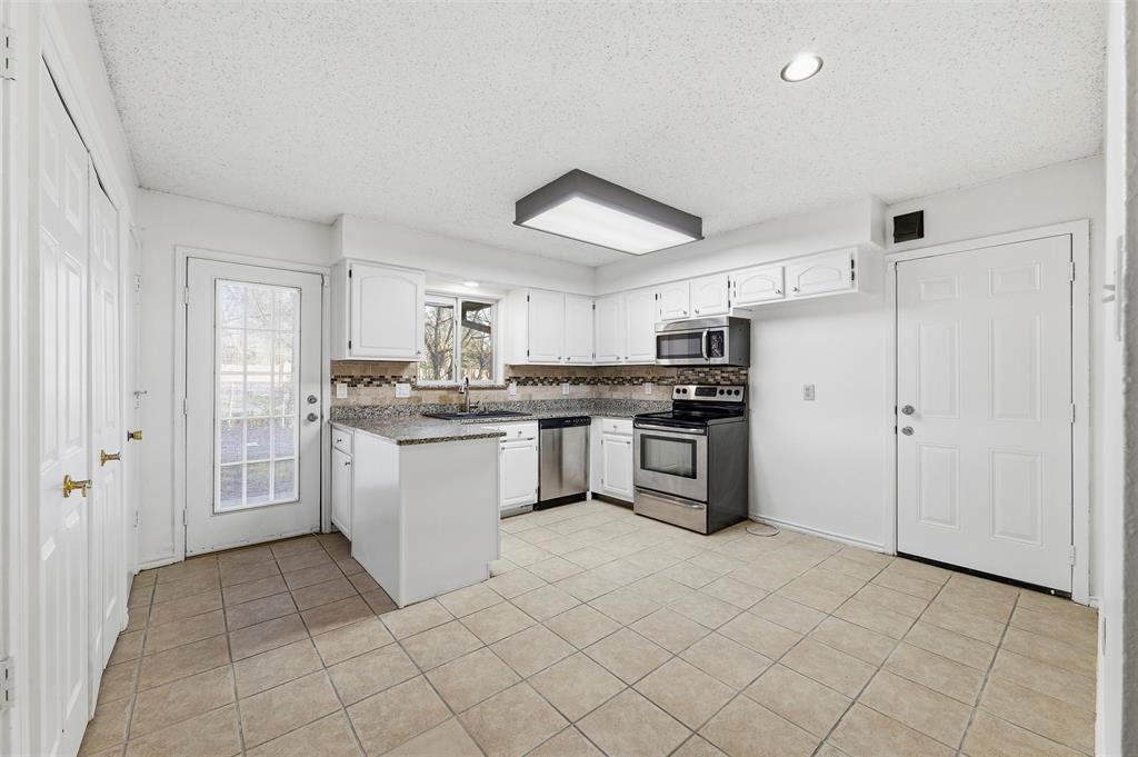 800 Howell Drive Coppell, TX 75019 - Photo 9 of 24 a kitchen with stainless steel appliances granite countertop a refrigerator sink and cabinets