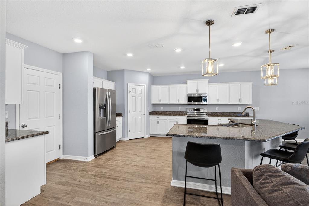 82 Berlin Avenue St. Cloud, FL 34771 - Photo 12 of 44 a kitchen with stainless steel appliances granite countertop a stove refrigerator a oven a sink with island chairs and wooden floor