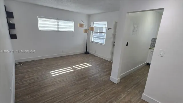 an empty room with wooden floor closet and windows