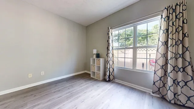 an empty room with wooden floor and windows