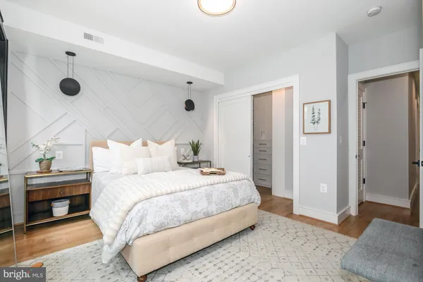 a bedroom with a bed and a lamp on dresser