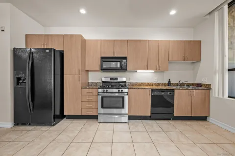 a kitchen with granite countertop a refrigerator and a stove top oven