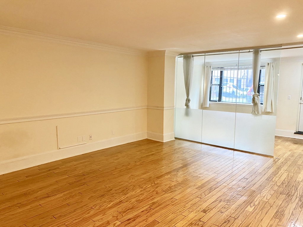 280 Commonwealth Avenue, Unit G8 Boston, MA 02116 - Photo 2 of 12 a view of an empty room with wooden floor and a window