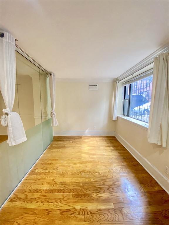 280 Commonwealth Avenue, Unit G8 Boston, MA 02116 - Photo 8 of 12 a view of an empty room with window and wooden floor