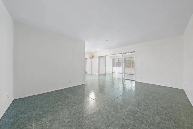 an empty room with chandelier fan and windows