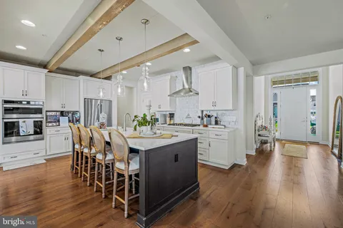 a kitchen with stainless steel appliances kitchen island granite countertop a table chairs sink and cabinets
