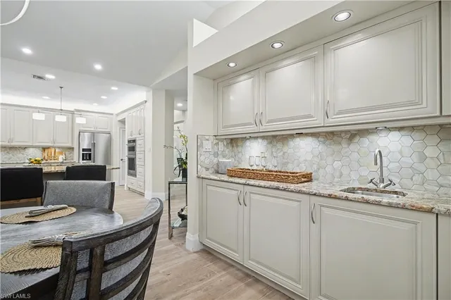 a kitchen with stainless steel appliances granite countertop a stove a refrigerator a sink a dining table and chairs