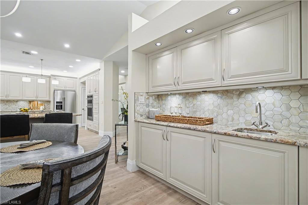 5186 Tallowood Way Naples, FL 34116 - Photo 13 of 50 a kitchen with stainless steel appliances granite countertop a stove a refrigerator a sink a dining table and chairs
