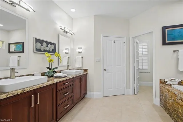 a spacious bathroom with a granite countertop double vanity sink a mirror and a