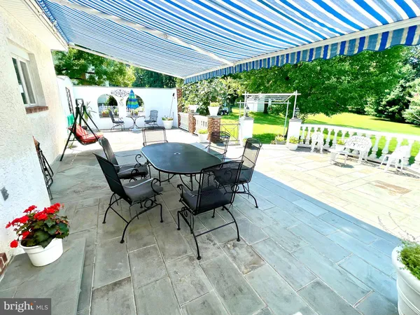 a view of a patio with table and chairs potted plants and large tree