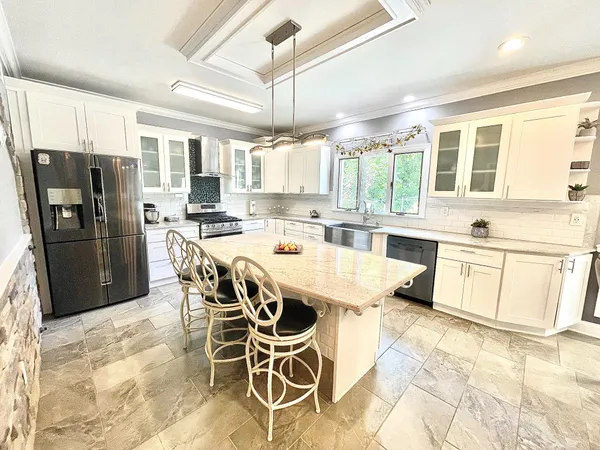 a kitchen with stainless steel appliances granite countertop a stove a refrigerator a sink a dining table and chairs with wooden floor