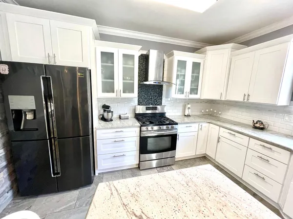 a kitchen with granite countertop a refrigerator stove and cabinets