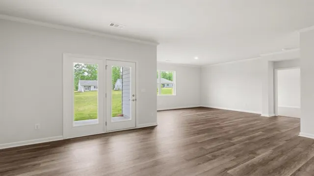 an empty room with wooden floor and windows