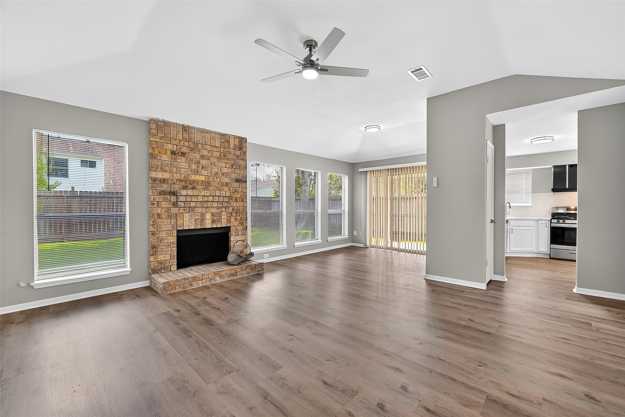 an empty room with wooden floor fireplace and windows