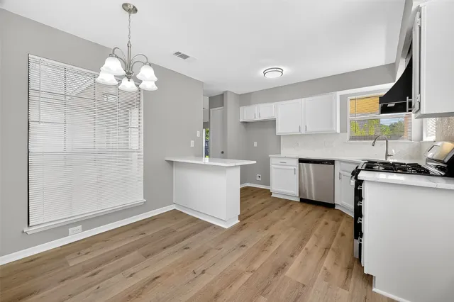 a kitchen with a refrigerator a sink dishwasher a stove and white cabinets with wooden floor