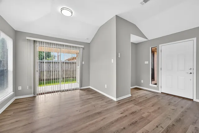 an empty room with wooden floor and windows