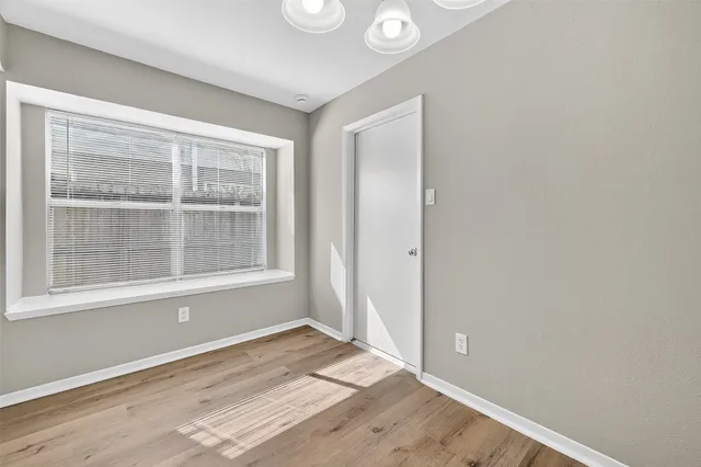 an empty room with wooden floor fireplace and windows