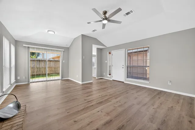 a view of an empty room with a window and wooden floor