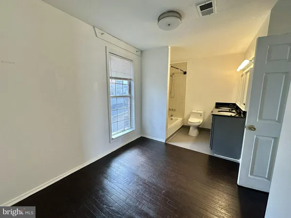 an empty room with wooden floor and a sink
