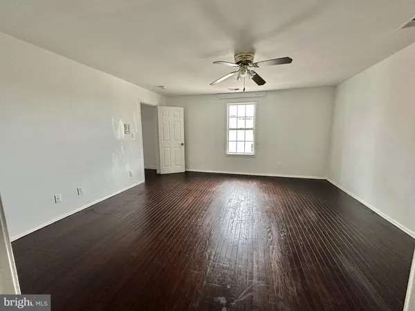 an empty room with wooden floor chandelier fan and windows