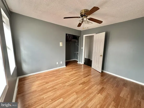 a view of empty room with wooden floor and fan