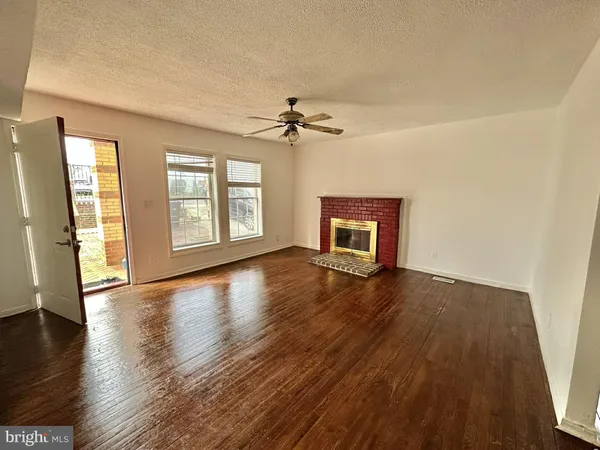 an empty room with wooden floor chandelier and windows